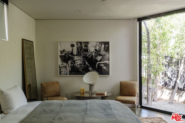 bedroom with concrete flooring and a wall of windows