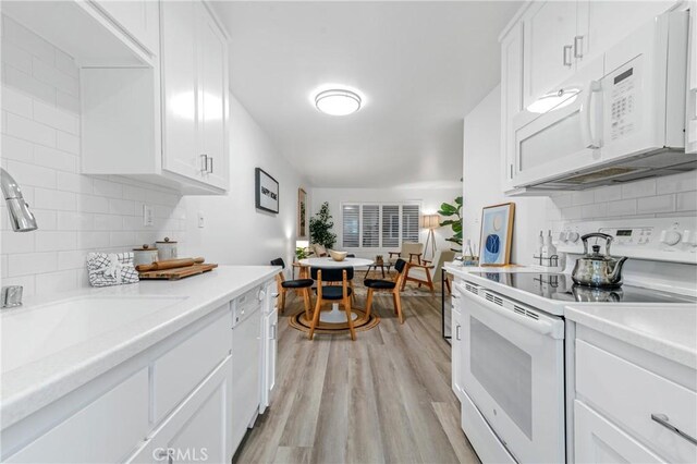 kitchen featuring light hardwood / wood-style floors, decorative backsplash, sink, white appliances, and white cabinets