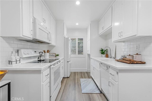 kitchen with white appliances, white cabinets, decorative backsplash, sink, and light hardwood / wood-style flooring