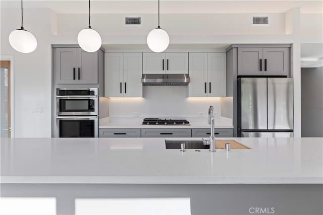 kitchen with stainless steel appliances, sink, pendant lighting, and gray cabinetry