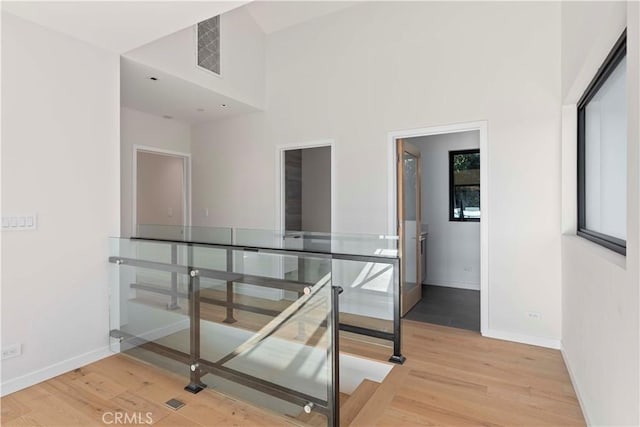 corridor featuring a high ceiling and light wood-type flooring