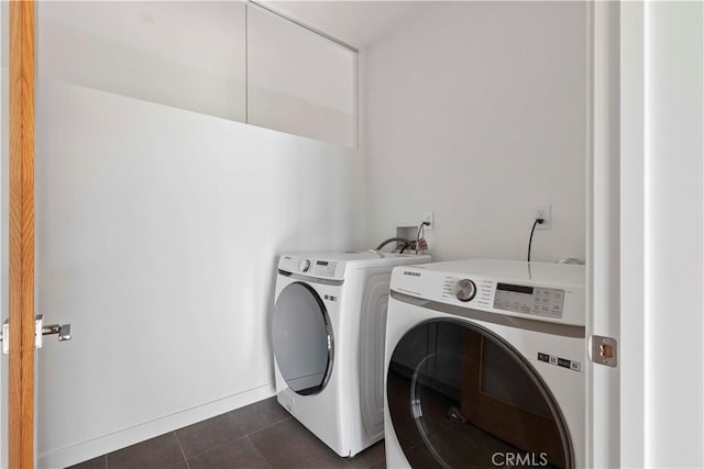 washroom featuring washing machine and dryer and dark tile patterned flooring