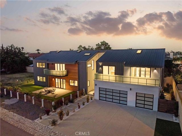 contemporary home with a balcony, a garage, and a patio