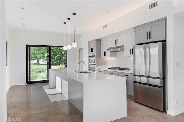 kitchen featuring decorative light fixtures, stainless steel appliances, gray cabinets, a kitchen island with sink, and sink