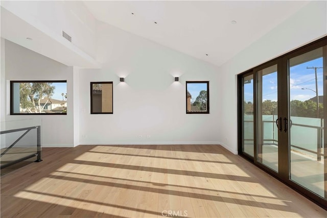 empty room with light hardwood / wood-style floors, french doors, and vaulted ceiling