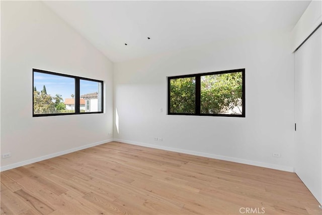 spare room with light hardwood / wood-style flooring and high vaulted ceiling