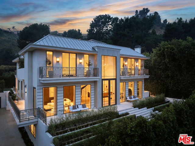 back house at dusk featuring a balcony