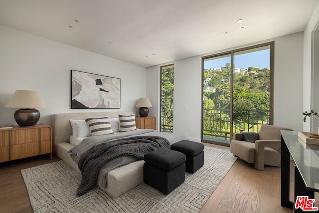 bedroom with hardwood / wood-style floors, access to outside, and expansive windows