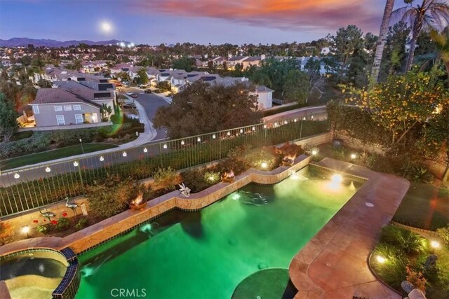 pool at dusk with an in ground hot tub