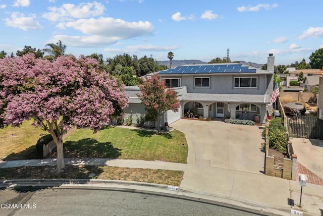 view of front of house featuring a garage, a front lawn, solar panels, and covered porch