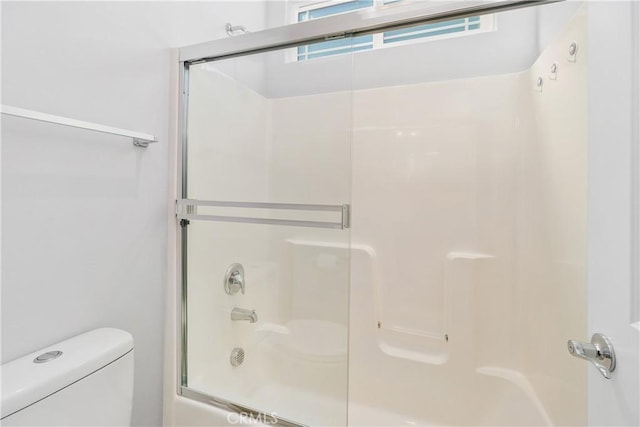 bathroom with toilet and bath / shower combo with glass door