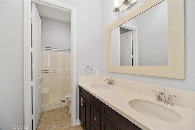 bathroom with a shower with door, vanity, and toilet