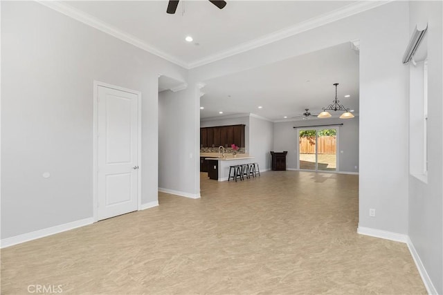 unfurnished living room featuring ceiling fan and ornamental molding