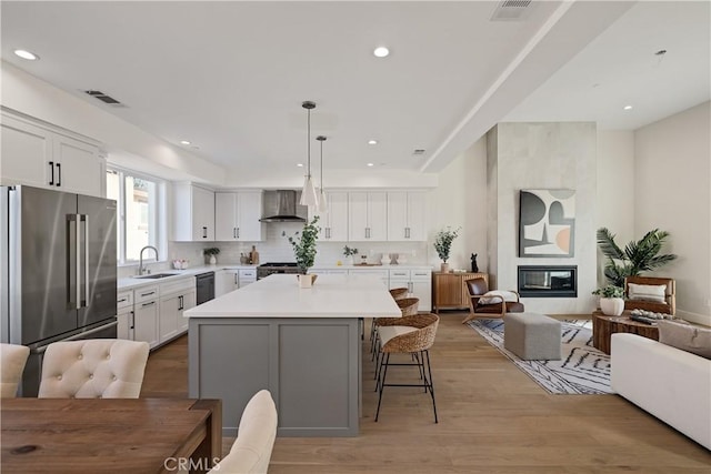 1700 Perkins Ln, Redondo Beach, CA 90278 - kitchen featuring appliances with stainless steel finishes, wall chimney range hood, a kitchen bar, a center island, and light countertops