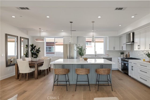 1700 Perkins Ln, Redondo Beach, CA 90278 - kitchen with appliances with stainless steel finishes, wall chimney exhaust hood, a kitchen island, a breakfast bar, and recessed lighting