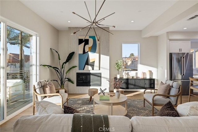 sitting room featuring light wood-type flooring, an inviting chandelier, and a large fireplace