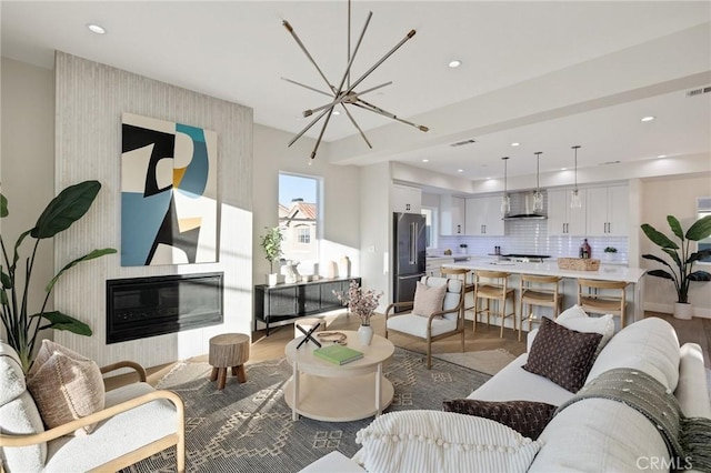 living room featuring a chandelier, light hardwood / wood-style floors, and a large fireplace