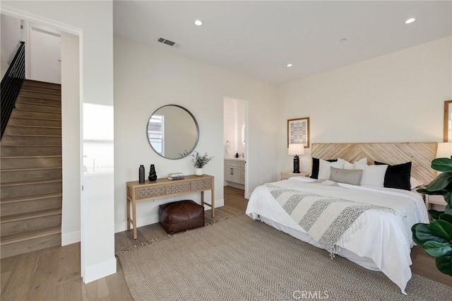 bedroom with connected bathroom and light hardwood / wood-style flooring