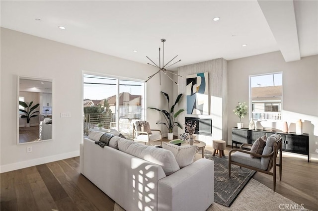 living room with dark wood-type flooring, beamed ceiling, plenty of natural light, and a notable chandelier