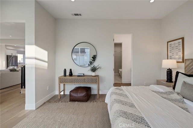 bedroom with light wood-type flooring and connected bathroom