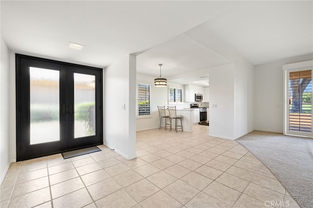 entrance foyer with a notable chandelier, french doors, and light carpet