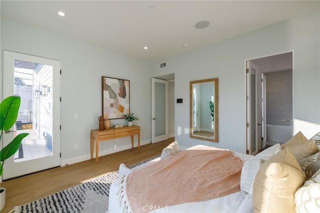 bedroom with ensuite bath and light hardwood / wood-style flooring