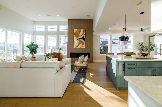 living room featuring a wealth of natural light, light wood-type flooring, sink, and a fireplace