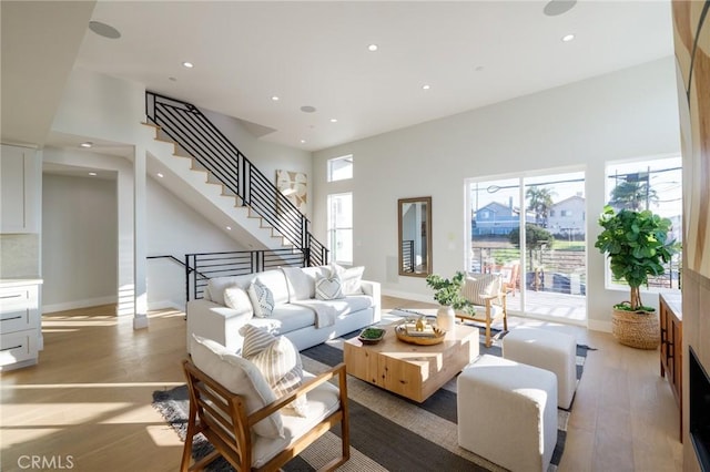 living room featuring a towering ceiling and light wood-type flooring