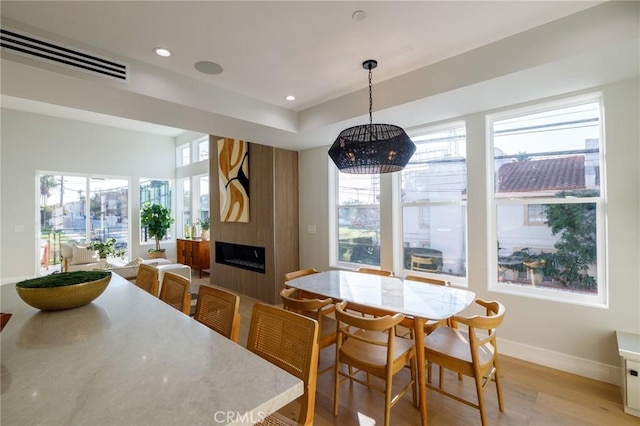 dining space featuring a large fireplace and light wood-type flooring