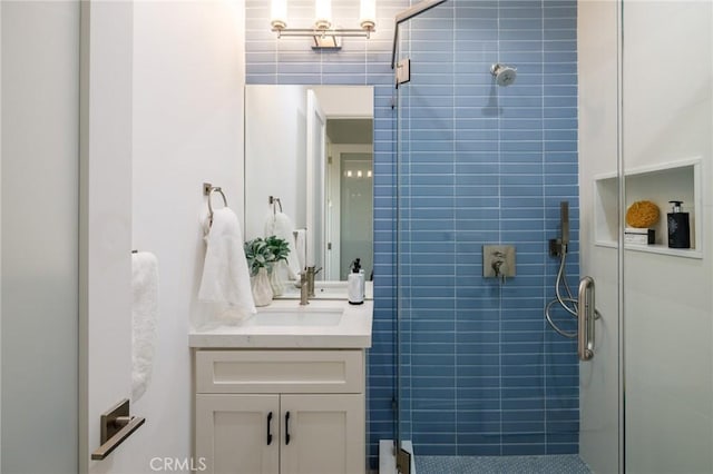 bathroom with vanity, a shower with door, and tile walls