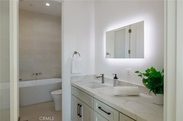 bathroom with a washtub, vanity, tile patterned floors, and toilet