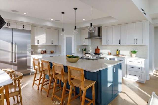 kitchen featuring wall chimney exhaust hood, white cabinetry, built in refrigerator, and decorative backsplash