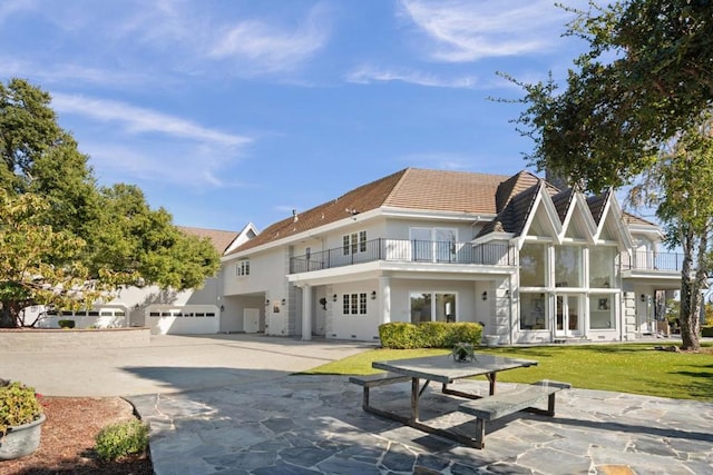 back of property with a yard, a balcony, and a garage