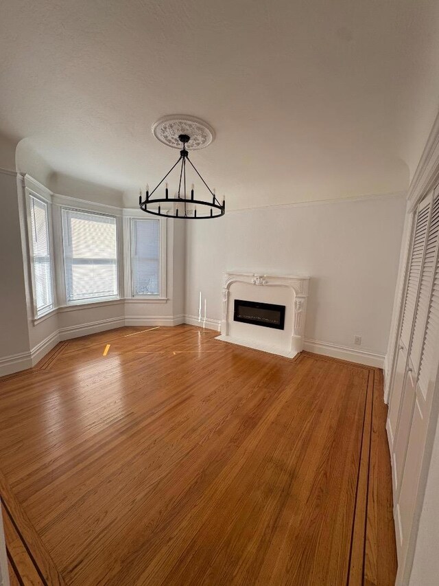 unfurnished living room featuring wood-type flooring and a notable chandelier