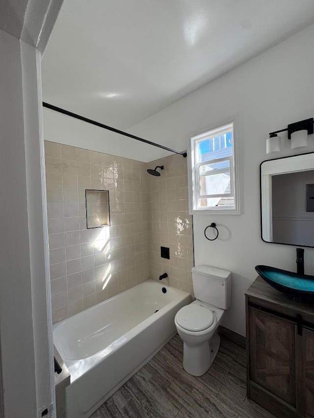 full bathroom with toilet, tiled shower / bath, hardwood / wood-style floors, and vanity