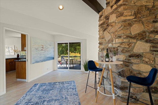 dining space with lofted ceiling with beams and light wood-type flooring