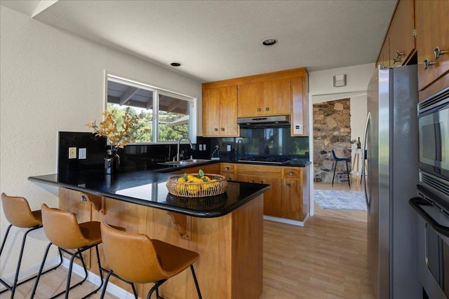 kitchen featuring sink, a breakfast bar area, kitchen peninsula, and appliances with stainless steel finishes