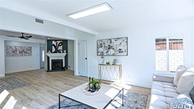 living room featuring light hardwood / wood-style flooring, a fireplace, and ceiling fan