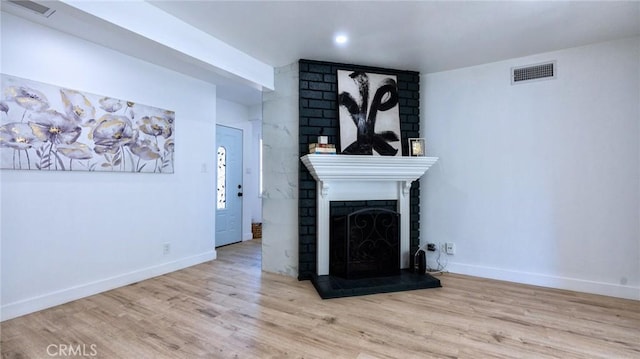 unfurnished living room featuring a fireplace and light hardwood / wood-style floors