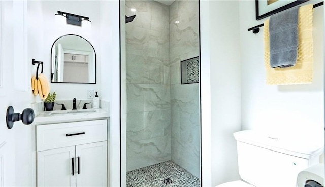 bathroom with vanity, toilet, and tiled shower