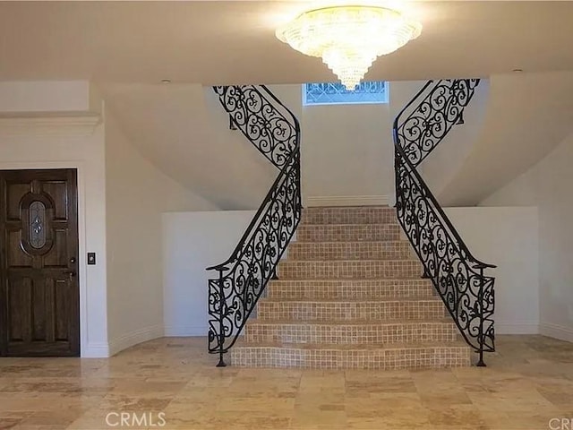 stairway featuring baseboards and an inviting chandelier