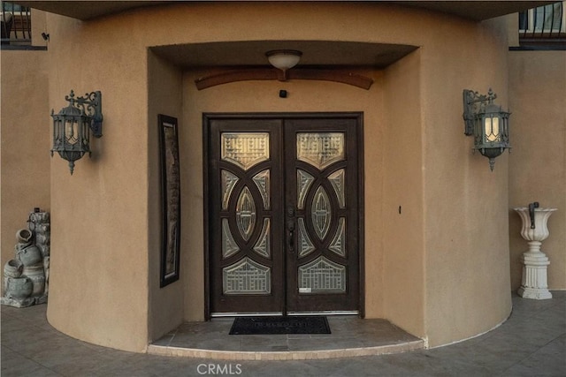 view of exterior entry with french doors and stucco siding