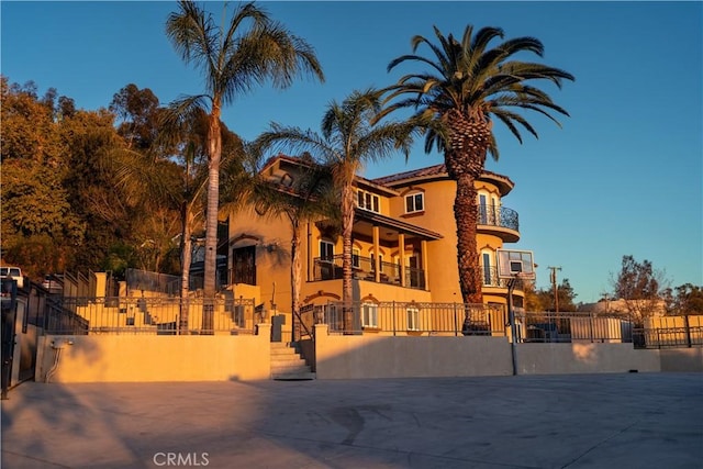 view of front of property with a fenced front yard, a balcony, and stucco siding