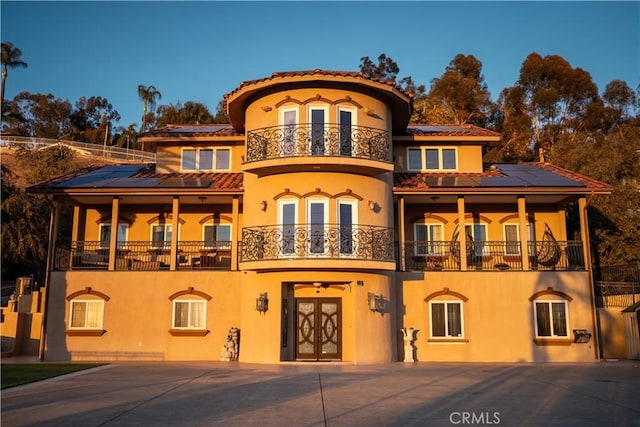 exterior space with french doors, a balcony, and solar panels