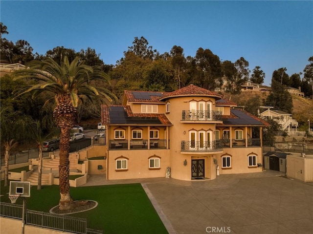 back of property with a yard, a patio, stucco siding, fence, and a balcony