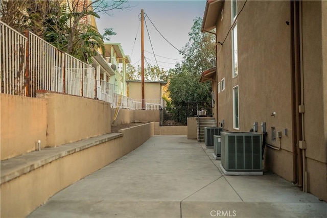 view of side of property with stucco siding, a patio area, fence, and central AC unit