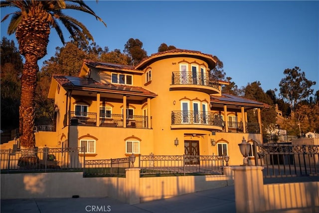 view of front of property with fence, a balcony, and stucco siding