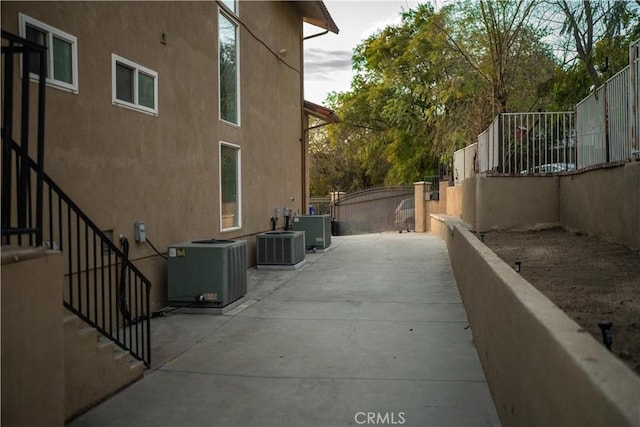 view of side of property featuring central AC, fence, and stucco siding