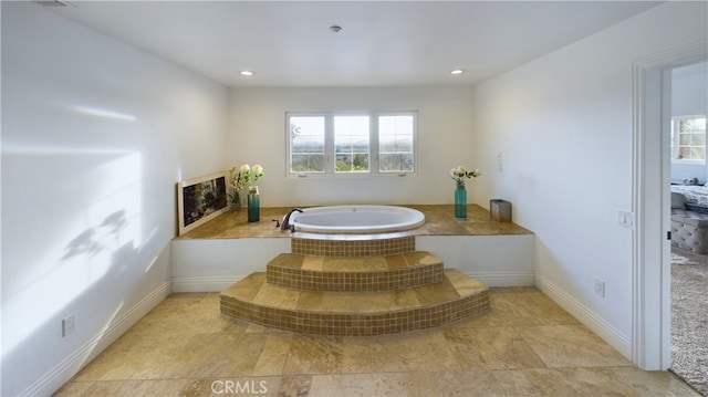 bathroom featuring baseboards, a bath, and recessed lighting