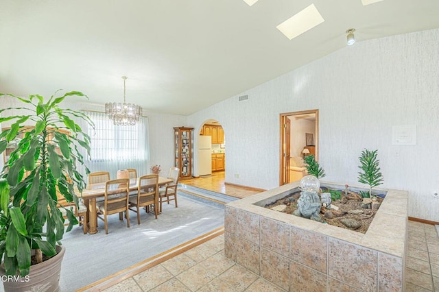 dining room featuring lofted ceiling with skylight and a chandelier